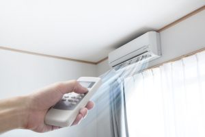 person-turning-on-a-ductless-air-handler-with-a-remote